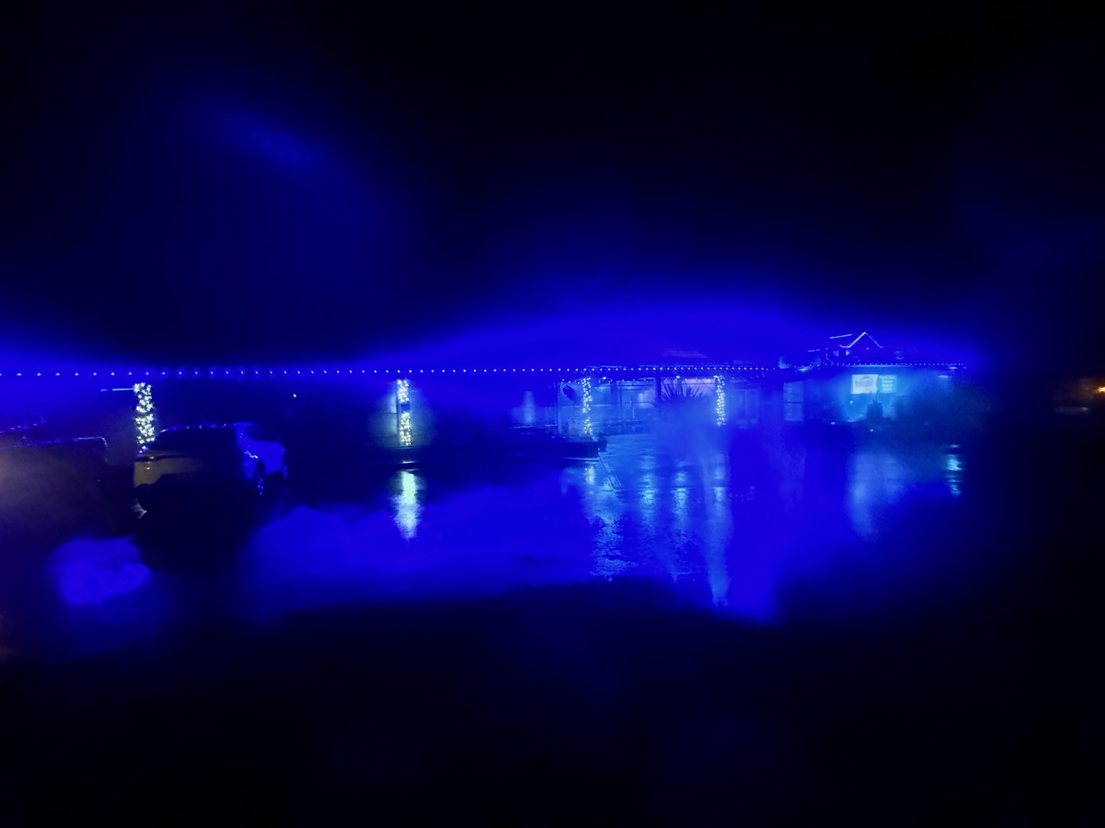 Blue roofline lighting reflecting off a wet parking lot