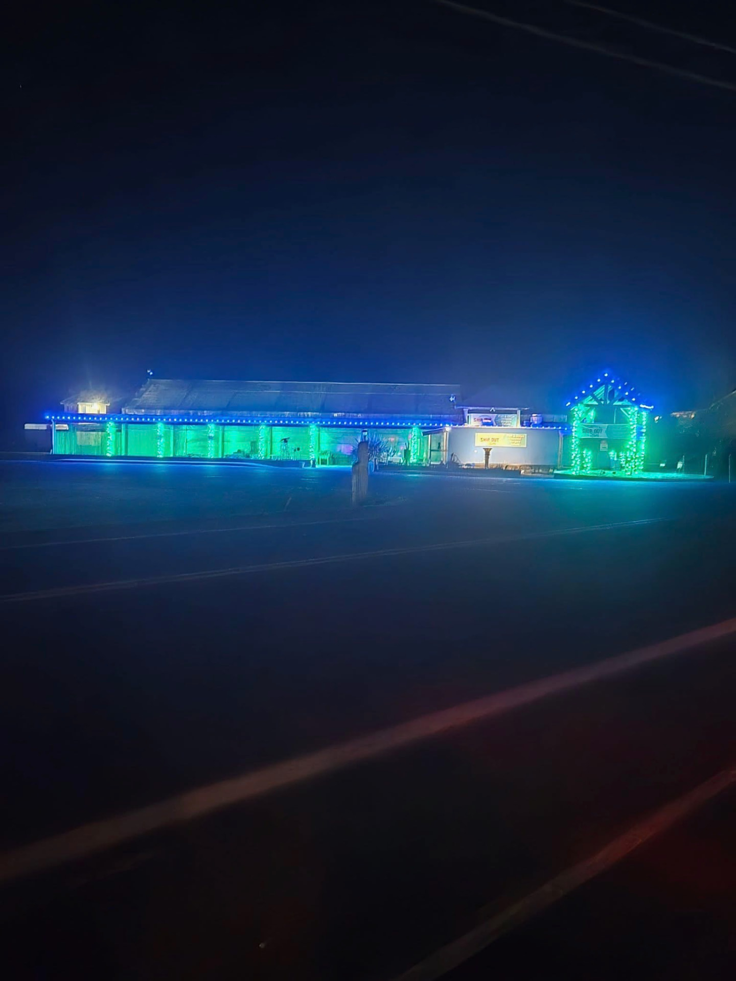 Storefront outlined in green and blue lights at night